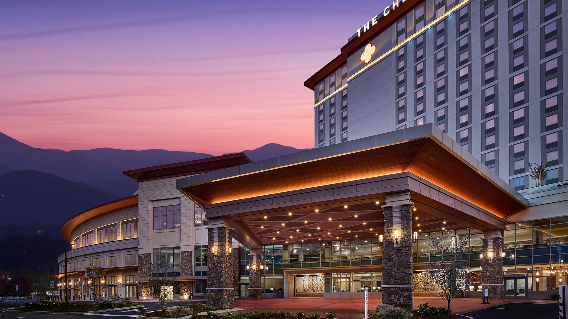 exterior of the cherokee casino and hotel with purple and pink sunset behind the mountains